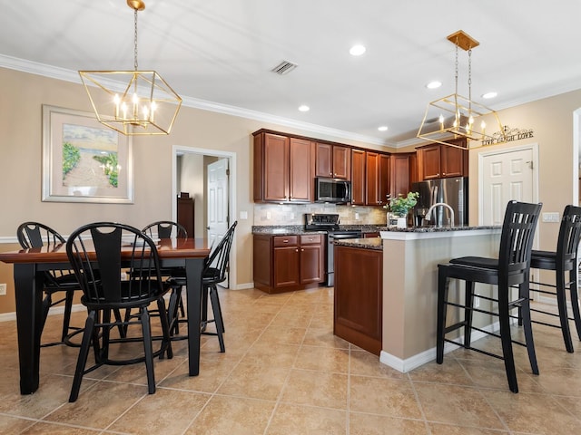 kitchen featuring a breakfast bar, crown molding, dark stone countertops, appliances with stainless steel finishes, and pendant lighting