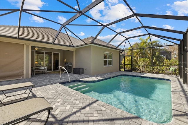 view of pool featuring a patio area, grilling area, glass enclosure, and ceiling fan