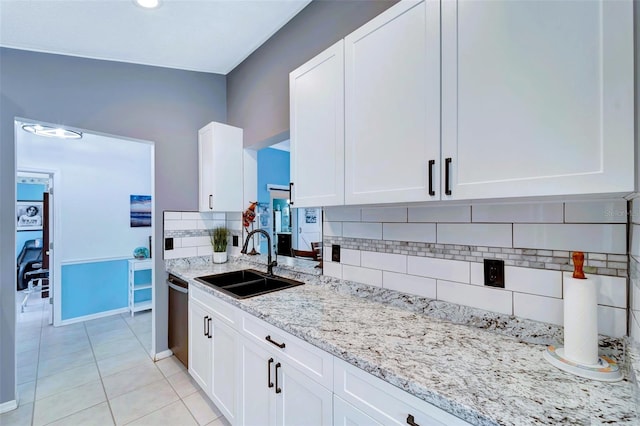 kitchen with backsplash, white cabinets, sink, stainless steel dishwasher, and light stone counters