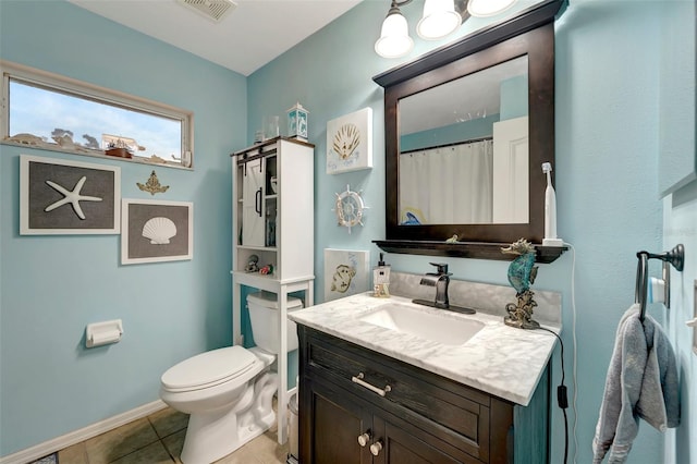 bathroom with toilet, vanity, and tile patterned floors