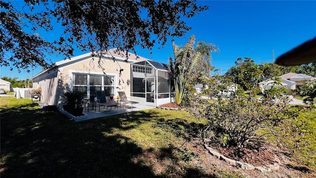 back of property featuring a yard, a patio, and glass enclosure