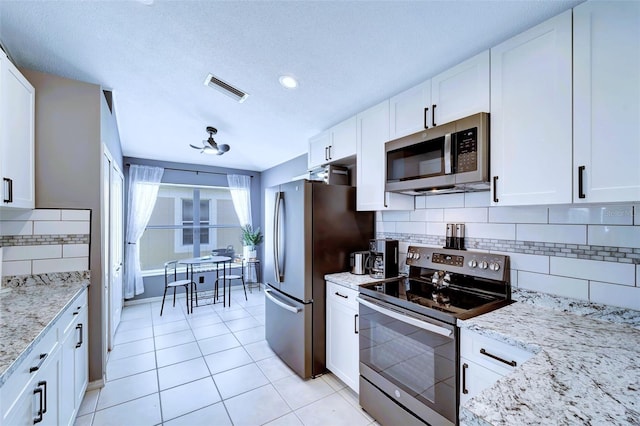 kitchen with white cabinets, decorative backsplash, light stone counters, and stainless steel appliances