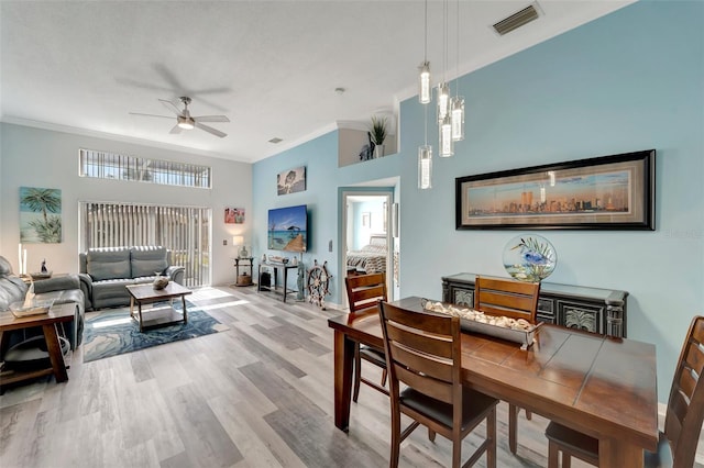 dining space with a towering ceiling, light hardwood / wood-style flooring, a wealth of natural light, and ceiling fan