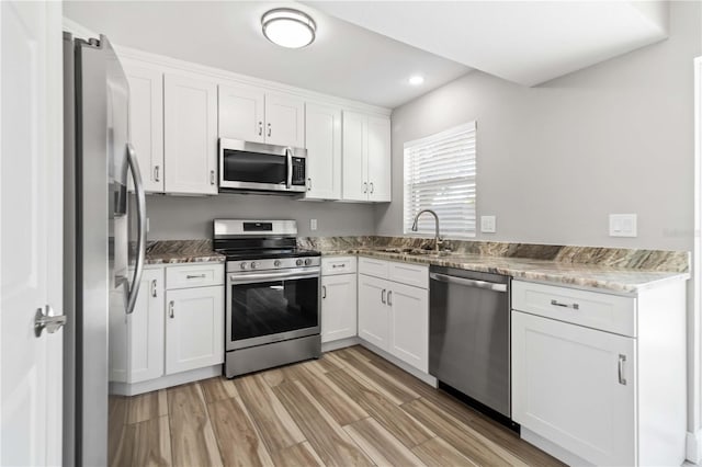 kitchen featuring sink, appliances with stainless steel finishes, white cabinetry, and light hardwood / wood-style floors