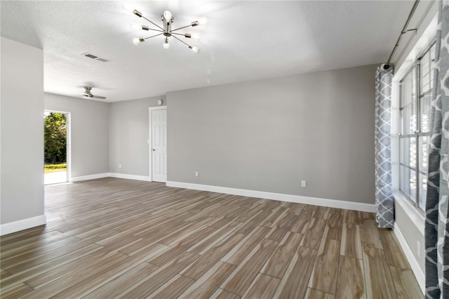 spare room with hardwood / wood-style flooring, a textured ceiling, and ceiling fan with notable chandelier