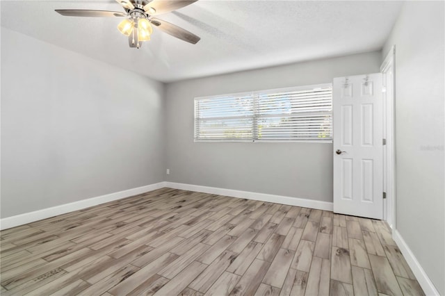 spare room featuring a textured ceiling, light wood-type flooring, and ceiling fan