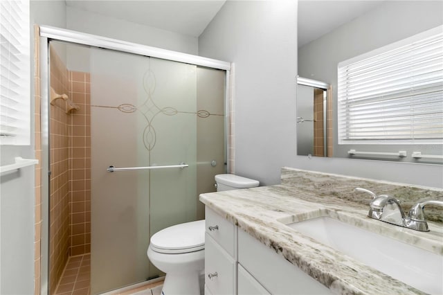 bathroom featuring toilet, a shower with shower door, vanity, and tile patterned floors