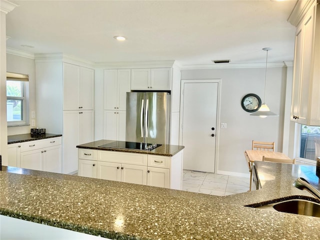 kitchen with black electric stovetop, hanging light fixtures, white cabinetry, and stainless steel fridge