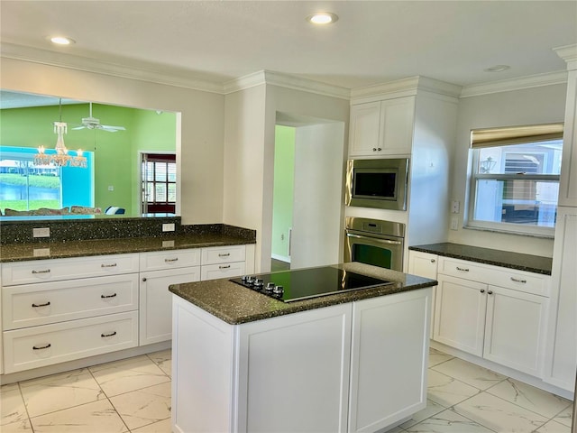 kitchen with appliances with stainless steel finishes, a center island, dark stone counters, and ornamental molding