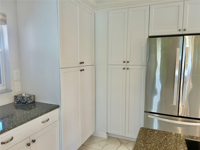 kitchen with white cabinets, dark stone counters, and stainless steel refrigerator