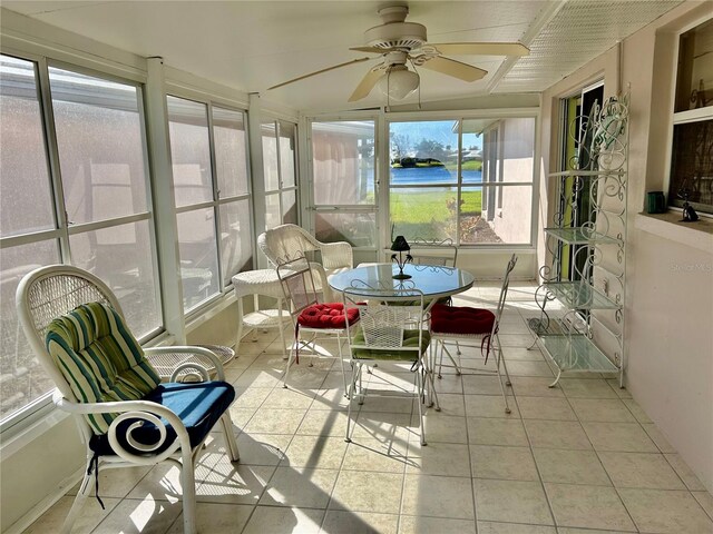 sunroom featuring a water view and ceiling fan