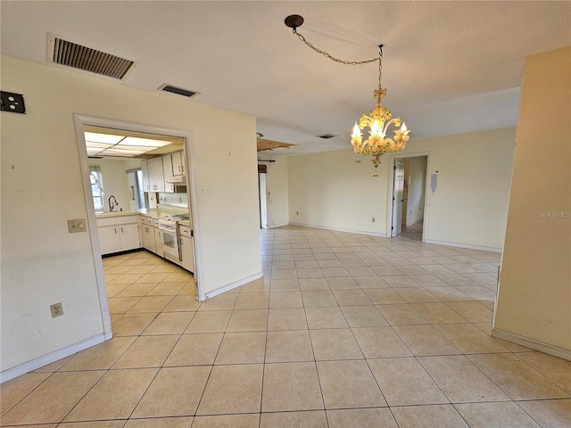 kitchen featuring light tile patterned flooring, a notable chandelier, pendant lighting, white cabinetry, and electric stove