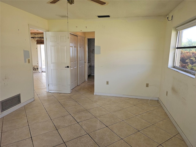 tiled empty room with a textured ceiling and ceiling fan