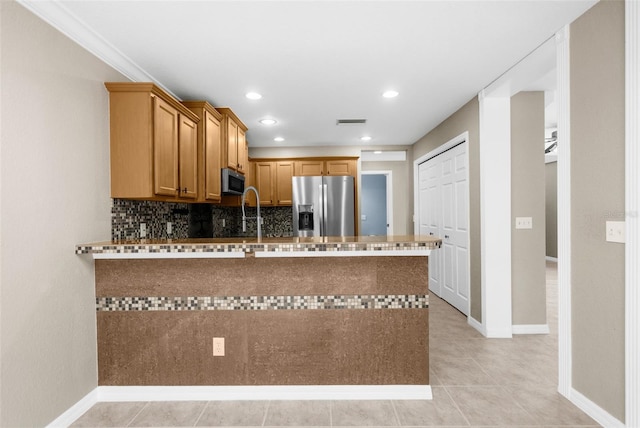 kitchen featuring kitchen peninsula, sink, light tile patterned floors, appliances with stainless steel finishes, and tasteful backsplash