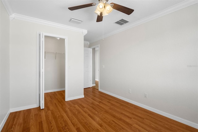 unfurnished bedroom with ornamental molding, light hardwood / wood-style flooring, a walk in closet, and ceiling fan