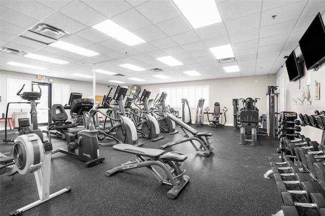 exercise room featuring a drop ceiling and a wealth of natural light