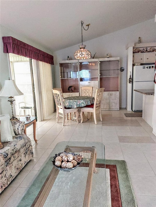 dining area featuring light tile patterned floors and vaulted ceiling