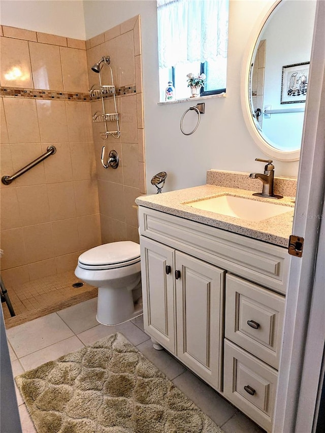 bathroom with tile patterned flooring, vanity, toilet, and tiled shower