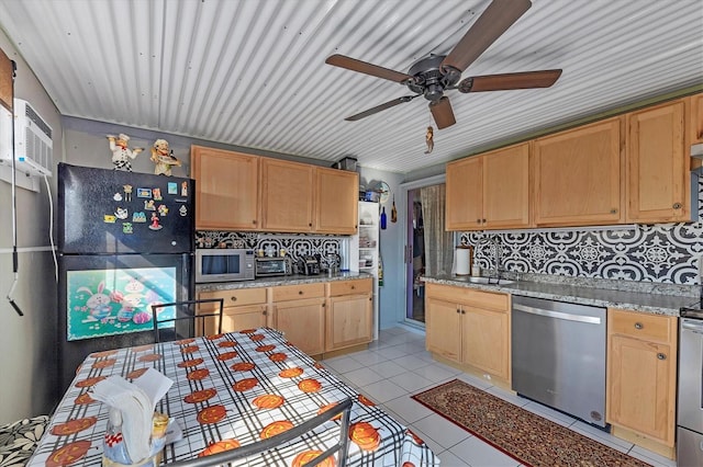 kitchen featuring backsplash, dishwasher, light stone counters, and black fridge