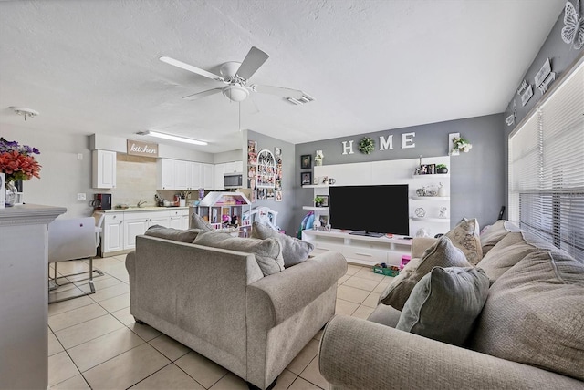 tiled living room featuring ceiling fan, a textured ceiling, and sink