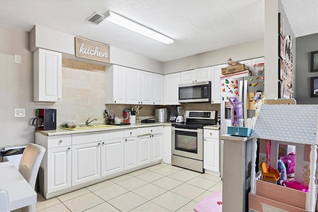 kitchen featuring stainless steel appliances, decorative backsplash, and white cabinets