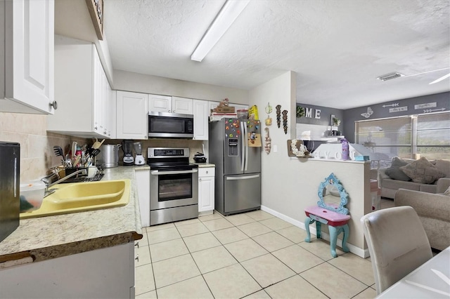 kitchen featuring appliances with stainless steel finishes, sink, backsplash, a textured ceiling, and white cabinetry