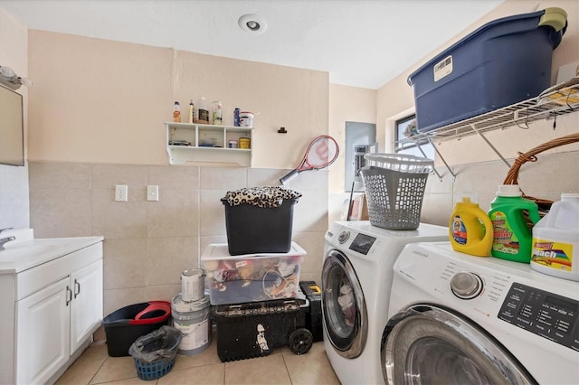 laundry area with tile walls, light tile patterned floors, separate washer and dryer, and cabinets