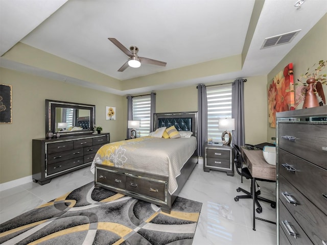 bedroom with ceiling fan and a tray ceiling