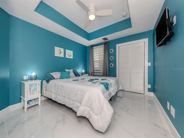 bedroom featuring ceiling fan, a closet, and a raised ceiling