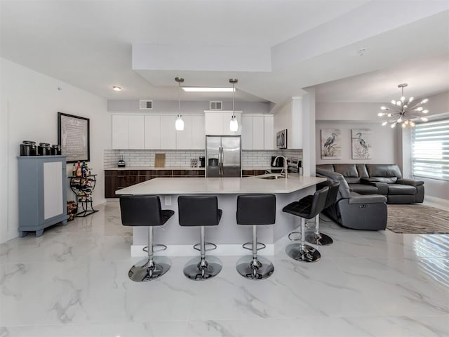 kitchen featuring white cabinets, tasteful backsplash, hanging light fixtures, and stainless steel appliances