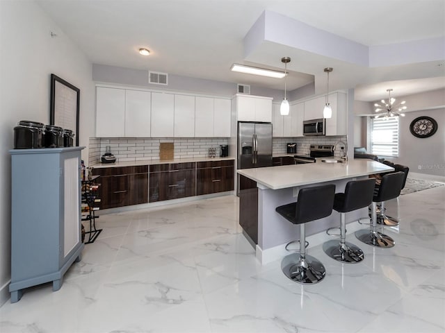 kitchen featuring tasteful backsplash, appliances with stainless steel finishes, decorative light fixtures, dark brown cabinetry, and sink