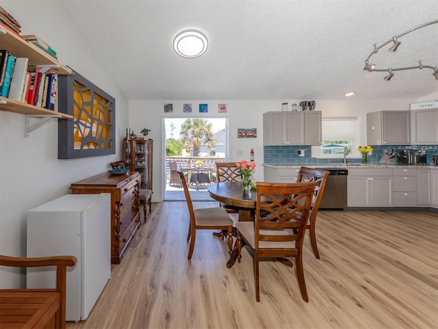 dining space with a textured ceiling, light hardwood / wood-style floors, and lofted ceiling