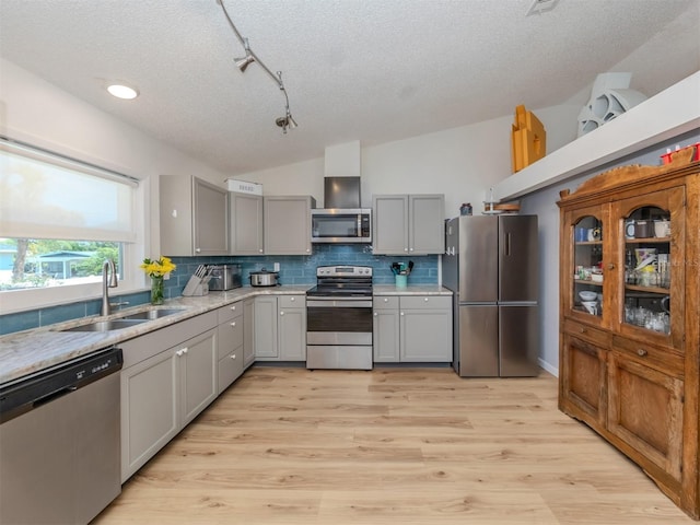 kitchen with light wood-type flooring, gray cabinetry, stainless steel appliances, vaulted ceiling, and sink