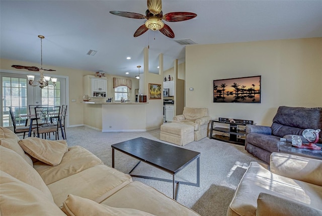 carpeted living room with lofted ceiling and ceiling fan with notable chandelier