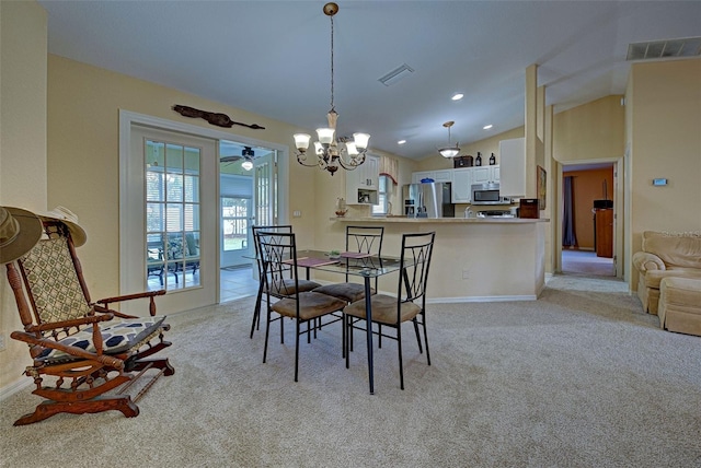 dining area with ceiling fan with notable chandelier, vaulted ceiling, and light colored carpet