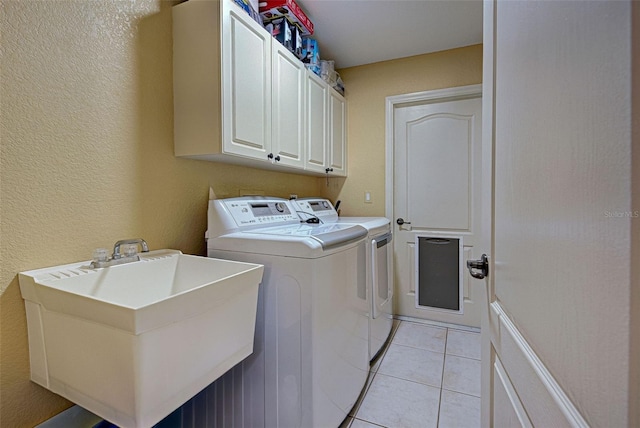 washroom featuring sink, washing machine and clothes dryer, light tile patterned floors, and cabinets