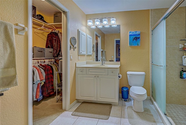 bathroom with vanity, toilet, tile patterned floors, and a shower with shower door