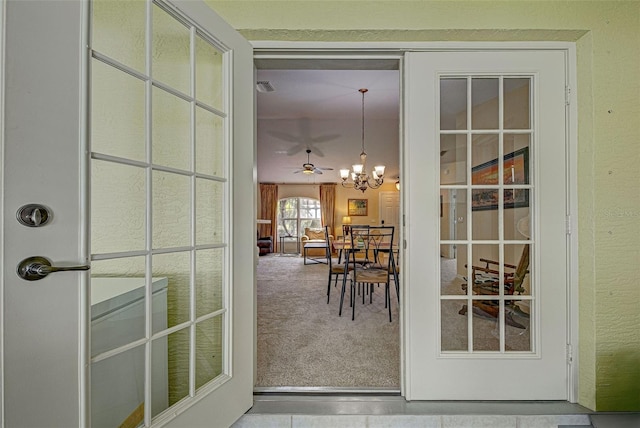 doorway to outside featuring carpet and ceiling fan with notable chandelier