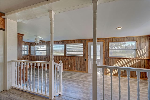 interior space with ceiling fan, wood-type flooring, a wealth of natural light, and wooden walls