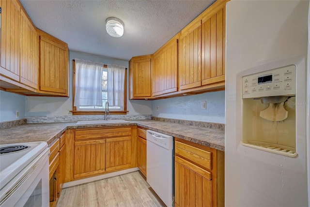 kitchen with sink, light hardwood / wood-style flooring, a textured ceiling, and white appliances