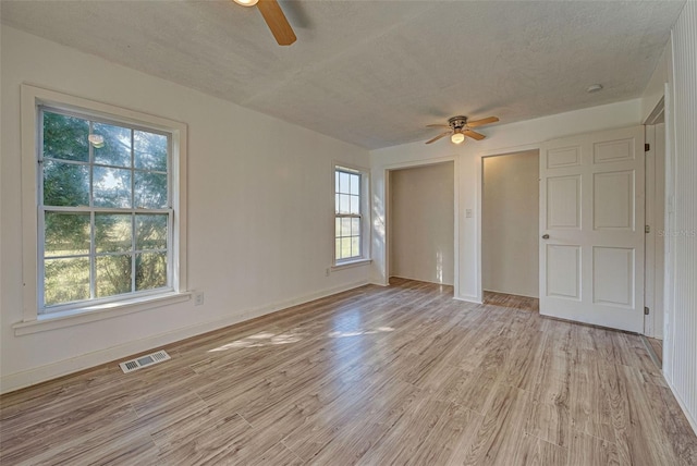 empty room with a textured ceiling, light hardwood / wood-style floors, and ceiling fan