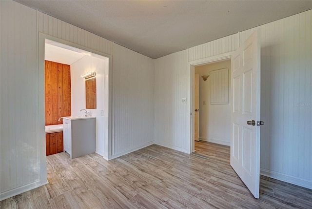 spare room with light hardwood / wood-style floors and wooden walls