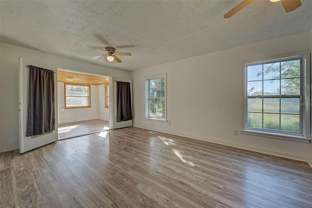 unfurnished room featuring light hardwood / wood-style floors, a textured ceiling, a wealth of natural light, and ceiling fan