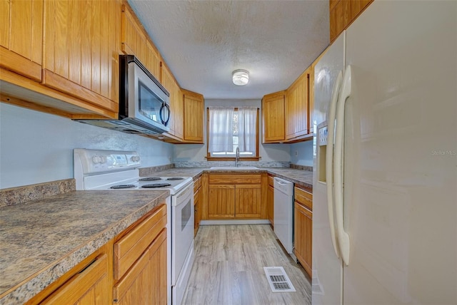 kitchen featuring white appliances, a textured ceiling, sink, and light wood-type flooring