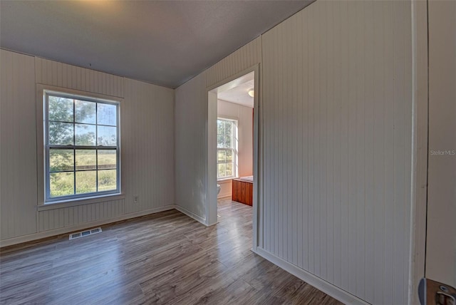 empty room with wooden walls and hardwood / wood-style flooring