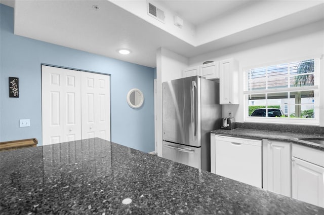 kitchen with white cabinetry, dark stone countertops, white dishwasher, and stainless steel fridge