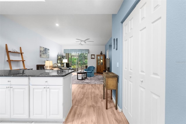 kitchen featuring light hardwood / wood-style flooring, white cabinetry, dark stone counters, and ceiling fan