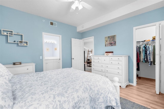 bedroom with ceiling fan, connected bathroom, light wood-type flooring, a closet, and a walk in closet