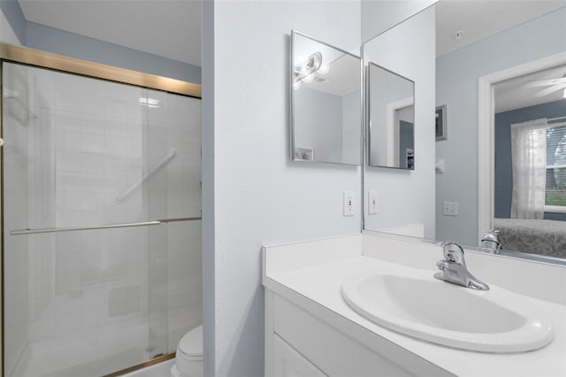 bathroom with vanity, ceiling fan, toilet, and walk in shower