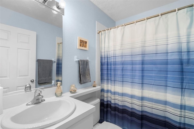 bathroom featuring toilet, a textured ceiling, a shower with curtain, and vanity